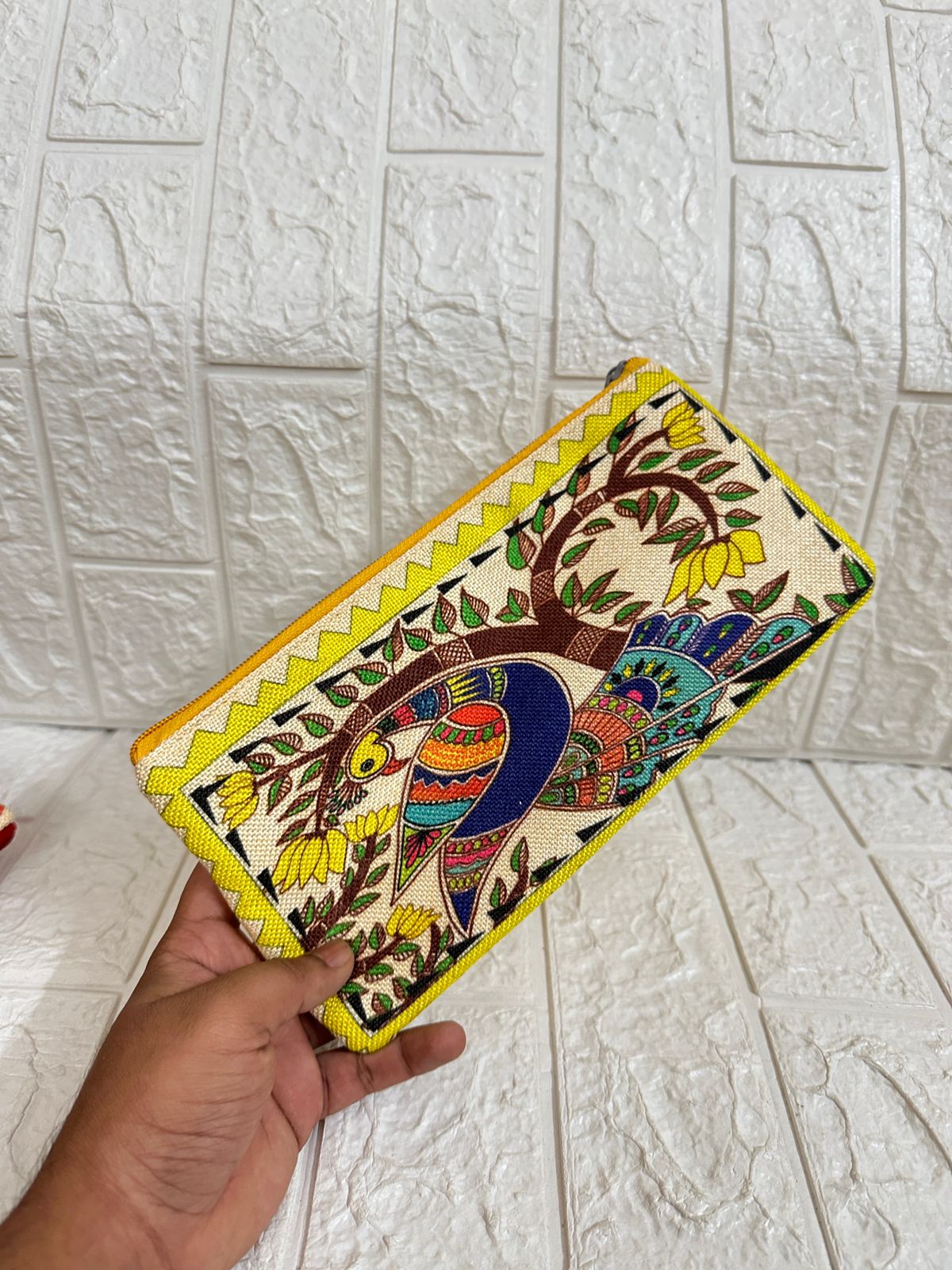 Handheld clutch with colorful bird design against a white tiled background