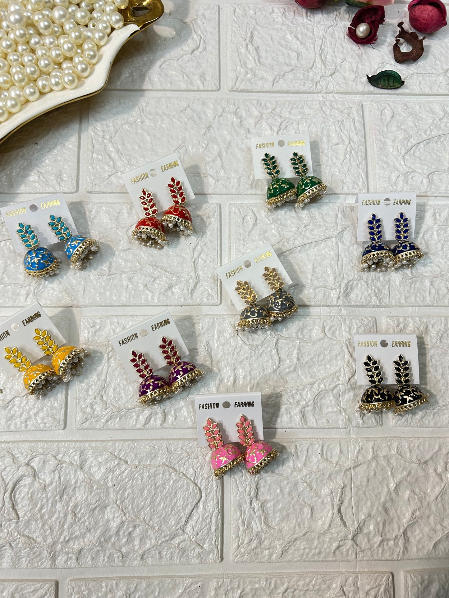 Colorful DesiTohfa Jhumki Earrings in various shades with intricate designs displayed on white textured background