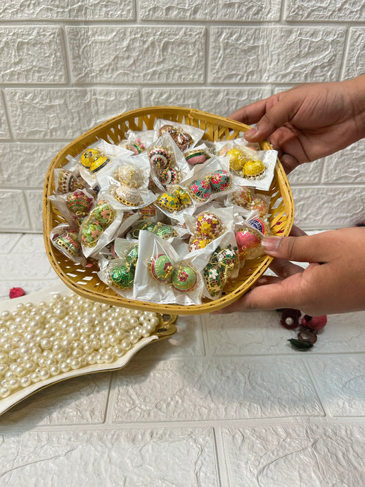 Basket of colorful Meenakari Jhumki Earrings held by hands with pearl jewelry in background