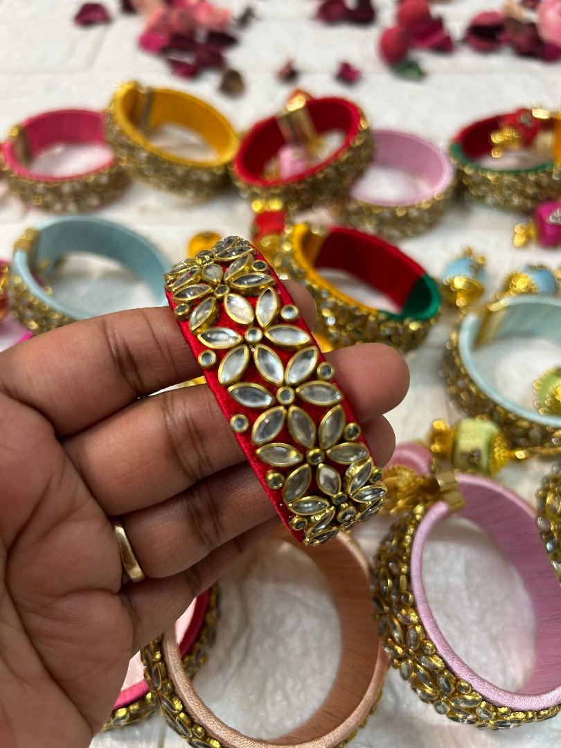 DesiTohfa Silk Thread openable Bangles with intricate floral gold and white stone design held in hand