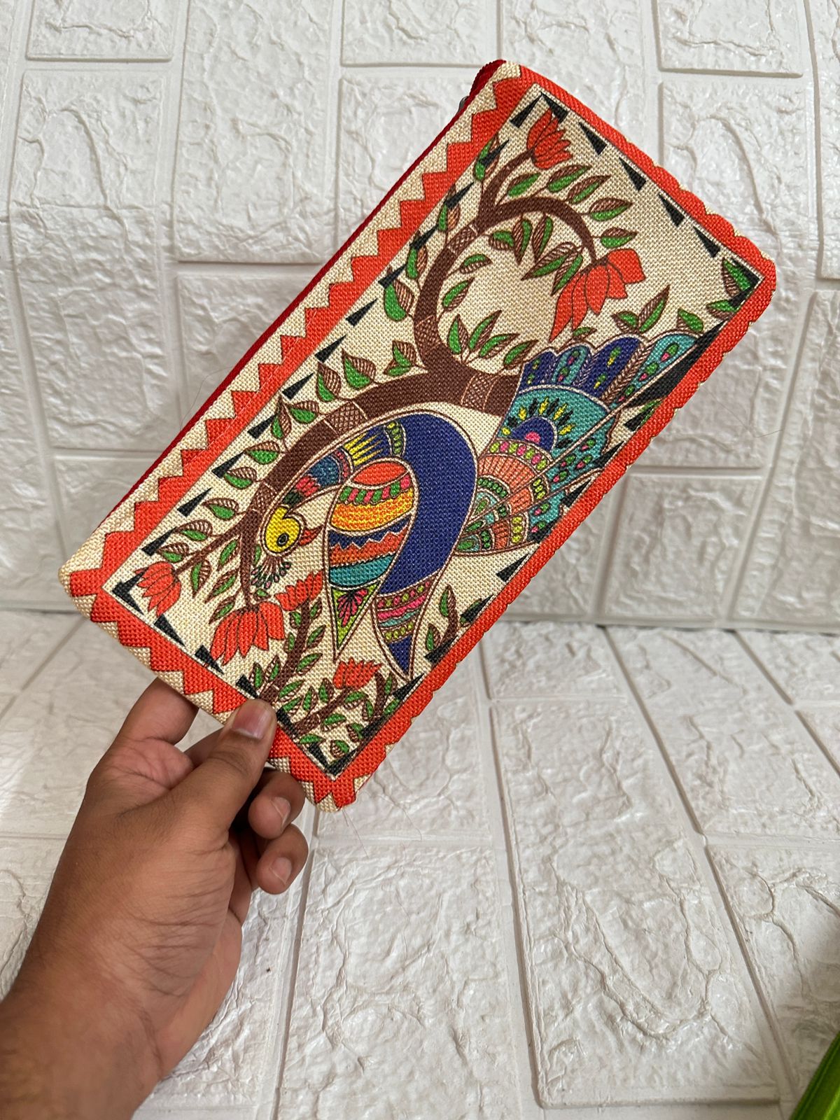Handheld clutch bag with colorful bird design on a textured white background