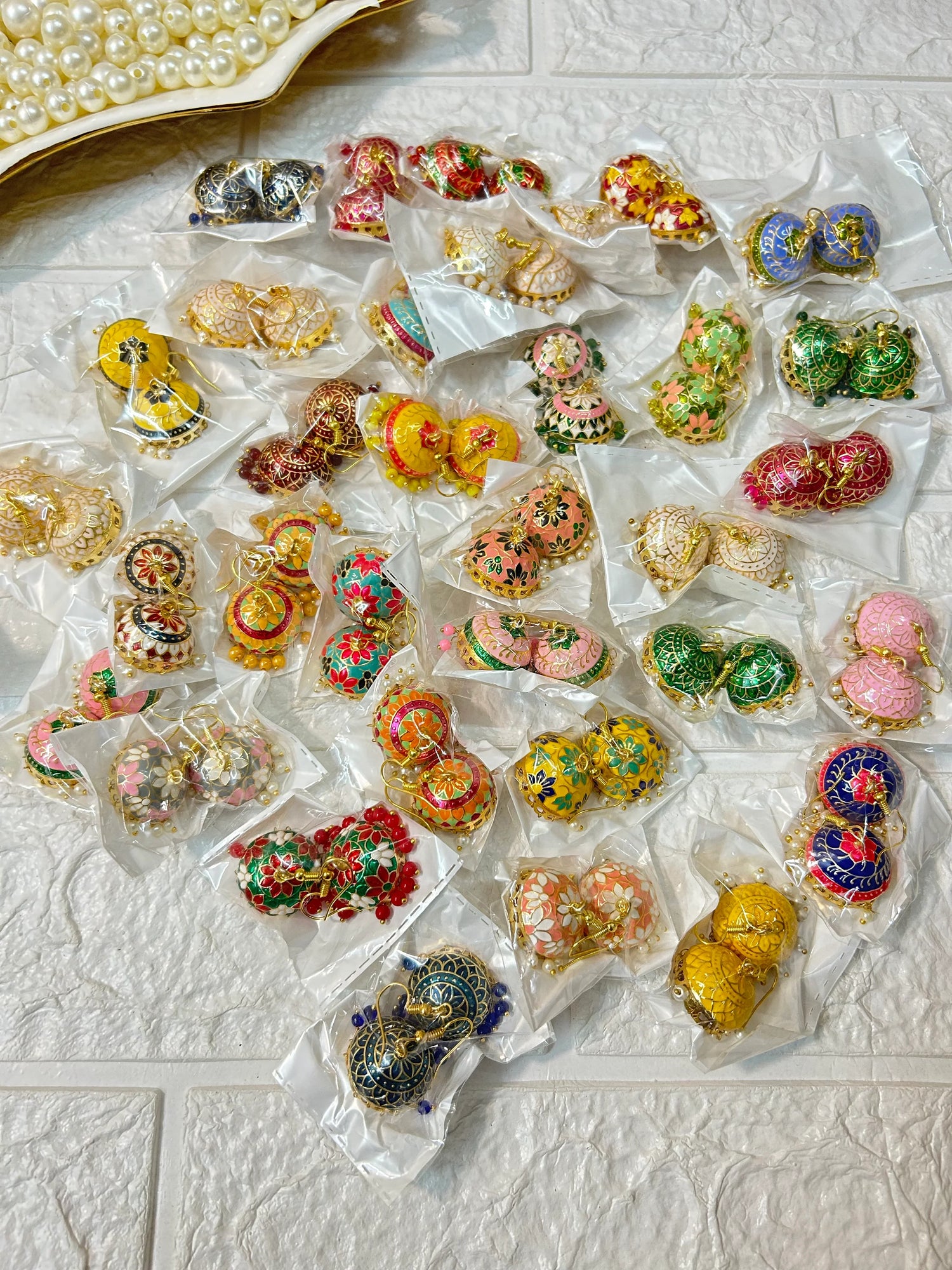 Colorful Meenakari Jhumki Earrings in various designs by DesiTohfa displayed in clear packaging on white textured surface