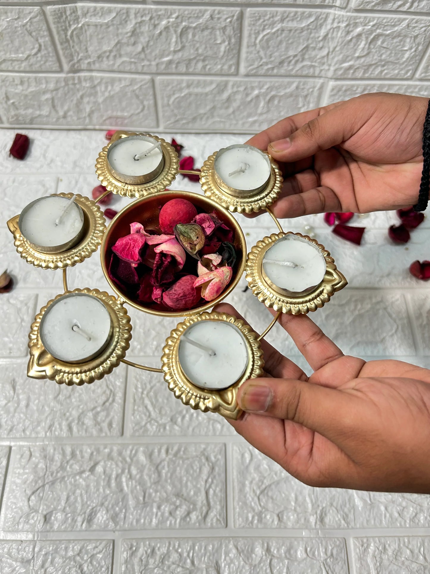 DesiTohfa Metal Urli candle holder with six white candles and central bowl holding dried rose petals