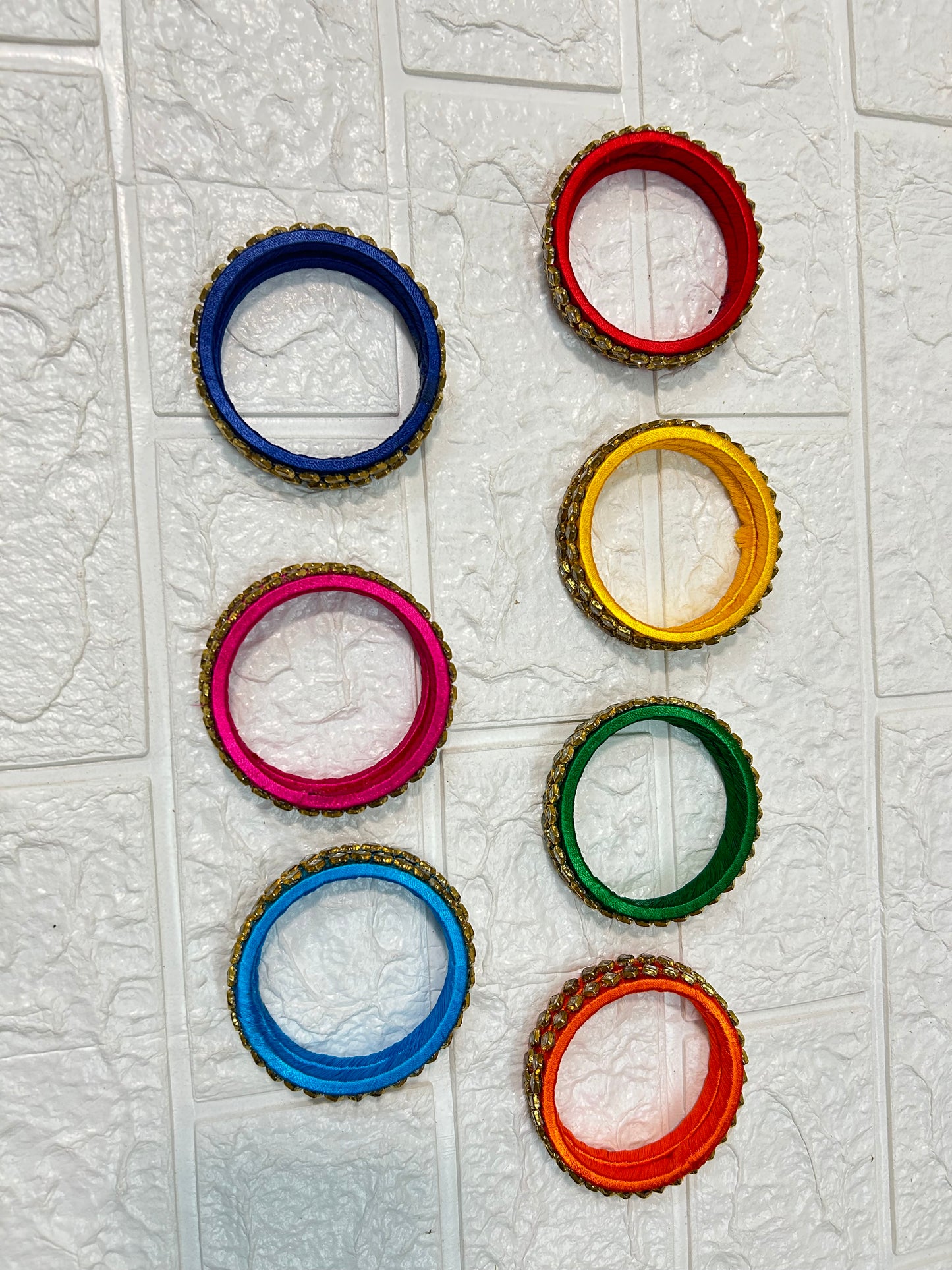 Colorful set of DesiTohfa Silk Thread Bangles in red blue yellow pink green and orange with decorative edging